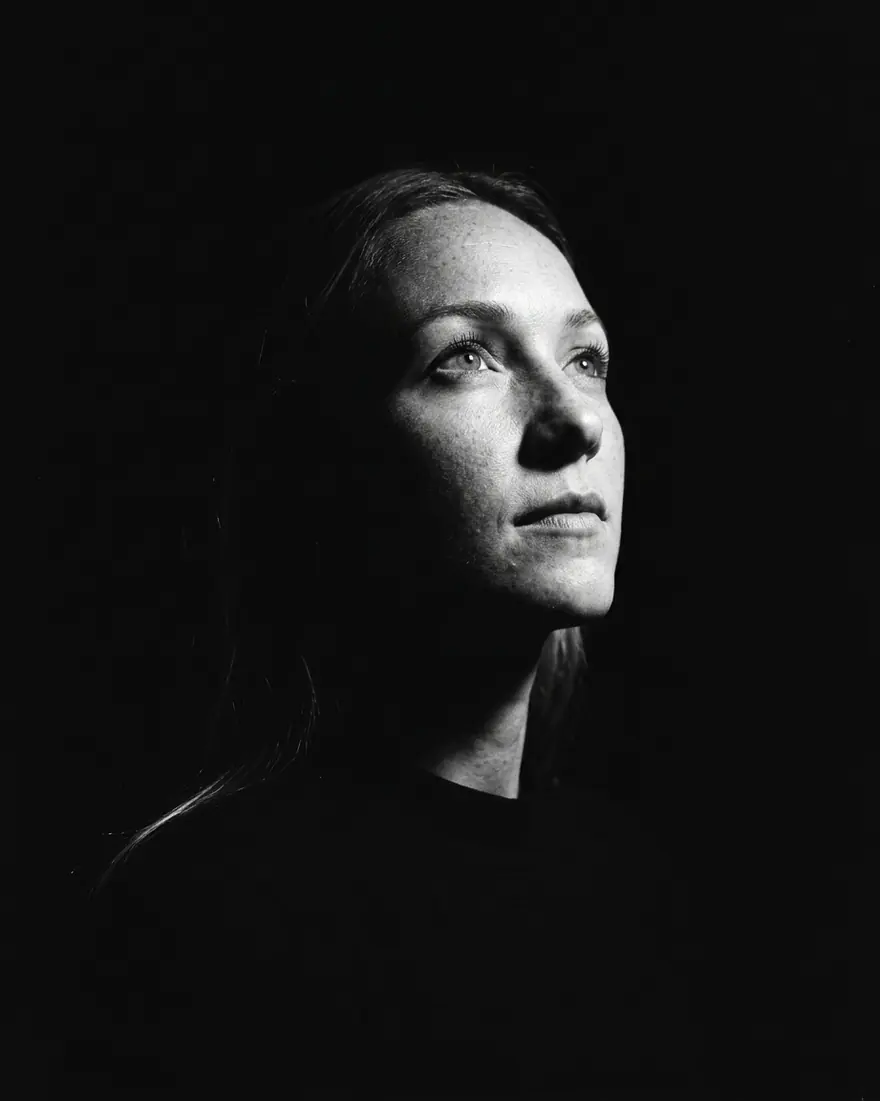 A black-and-white cinematic noir portrait lit by a single hard light.
